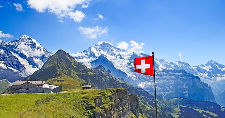 Green alpine meadows below snow-capped mountain peaks