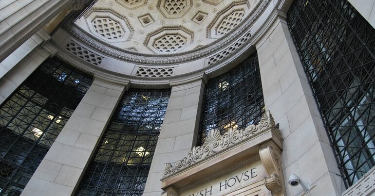 A grand stone building facade with an arched entrance, seen from below